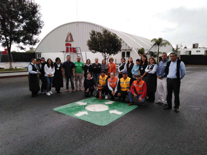 Brigada interna de protección civil en capacitación práctica con extintor en punto de reunión
